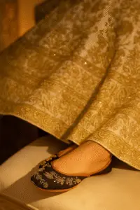 "Black embroidered khussa shoes for women paired with traditional lehenga, handcrafted ethnic footwear with silver threadwork for weddings and festive wear.