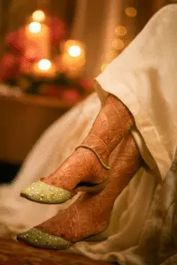 Green embellished khussa shoes paired with patterned stockings and white ethnic wear, captured in a warm candlelit setting—ideal for festive fashion, handcrafted footwear, and traditional Pakistani style.