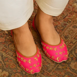 Bright pink embroidered khussa shoes with gold floral and butterfly motifs, traditional Indian jutti style for festive and bridal wear