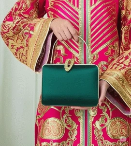 Traditional red embroidered outfit with gold detailing, paired with elegant green handbag featuring gold clasp – fusion of ethnic fashion and modern accessories