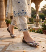 Bridal khussa shoes Pakistan worn with cream embroidered outfit near garden fountain
