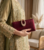 Woman holding maroon bridal party clutch bag with sage green embroidered dress