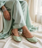 Mint green sequin khussa paired with silver anklet in sitting pose
