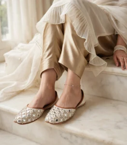 Mirror work bridal khussa flats paired with gold satin pants and pearl bracelet