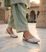 Woman wearing mirror work bridal khussa with green embroidered outfit