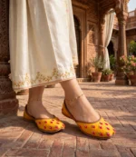 Woman walking in mustard bridal jutti near Mughal haveli pillars