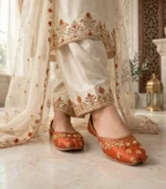 Woman wearing rust bridal khussa with cream dress