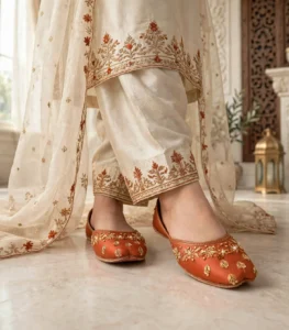 Woman wearing rust bridal khussa with cream dress