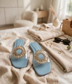 Light blue fancy flat sandals styled with beige linen outfit, sunglasses and straw bag