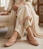 Woman seated wearing bridal khussa for women paired with anklet and ivory outfit