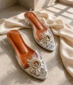 Crystal embellished clear women's slippers with low transparent block heel on stone surface
