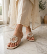 Woman wearing crystal party wear sandals with cream embroidered shalwar kameez on marble floor