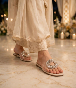 Cream crystal flat slides with transparent strap worn at an evening wedding event