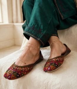 Close-up of embroidered khussa for women paired with gold anklets and green kurta