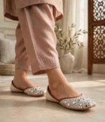 Woman wearing embroidered ivory khussa with pink shalwar indoors