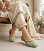 Embroidered sage green khussa styled with a cream shalwar kameez