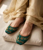 Close-up of emerald green bridal khussa with tan leather trim and anklet