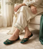 Woman wearing emerald green bridal khussa with cream shalwar kameez