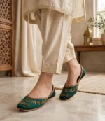 Emerald green bridal khussa styled with golden trousers, walking pose