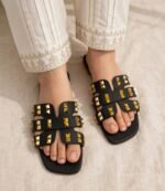 Women's gold studded flat slide sandals styled with white embroidered pleated trousers