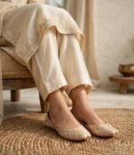 Woman wearing ivory gold khussa for women with a cream embroidered shalwar kameez