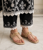 Ladies beige flat sandals with gold buckle styled with black embroidered lace trousers