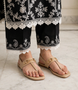 Ladies beige flat sandals with gold buckle styled with black embroidered lace trousers