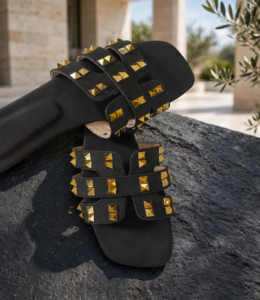 Pair of black ladies flat sandals with golden studs and H-band cut-out design