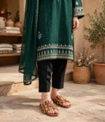 Gold studded tan flat sandals worn with an emerald green embroidered kurta and black trousers