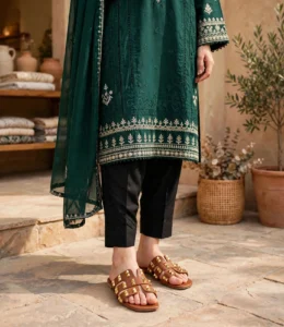 Gold studded tan flat sandals worn with an emerald green embroidered kurta and black trousers