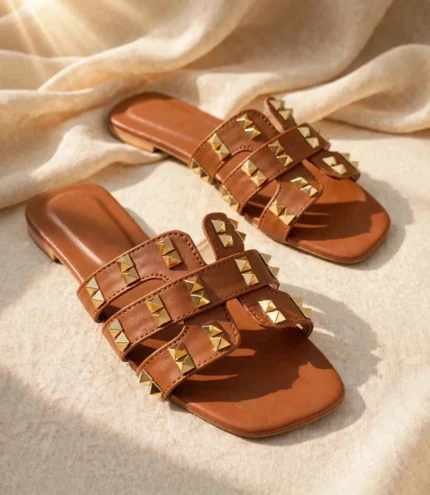 Pair of tan brown ladies studded flat sandals with gold pyramid studs and square toe