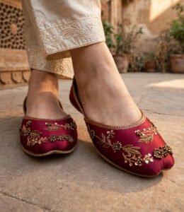 Close-up of handmade maroon khussa with antique gold beadwork, sequins and leaf embroidery