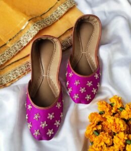 Flat lay of pearl work bridal khussa pair showing floral embroidery and tan leather trim