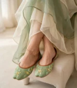 Woman wearing sage green embroidered khussa with thin flat sole and gold anklet