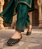Traditional Pakistani footwear in black and gold worn with green silk suit