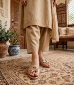Woman wearing transparent crystal flat sandals with beige embroidered shalwar kameez