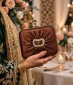 Woman holding copper bridal clutch bag with henna hands and green wedding outfit