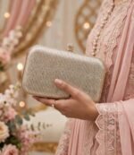 Woman holding bridal clutch bag with pink embroidered wedding suit