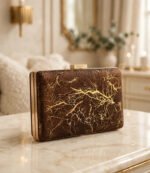 Brown gold box clutch bag for women displayed on a marble table