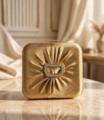 Gold pleated party wear clutch with sparkling stone buckle on marble surface