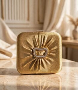 Gold pleated party wear clutch with sparkling stone buckle on marble surface