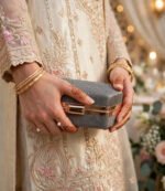 Girl with mehndi hands holding grey shimmer wedding clutch bag with gold bangles