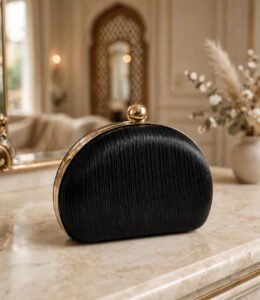 Black pleated half moon ladies evening clutch bag with gold ball clasp on marble