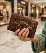 Ladies evening clutch bag with gold frame held in hand at a shopping mall