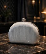 Silver pleated ladies evening clutch bag with chrome ball clasp on dark marble
