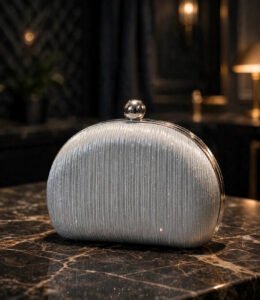 Silver pleated ladies evening clutch bag with chrome ball clasp on dark marble