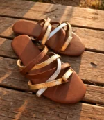 Ladies gold and silver toe ring flat chappal placed on a wooden surface
