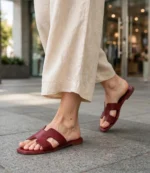 Woman walking in maroon ladies flat sandals with cream linen trousers