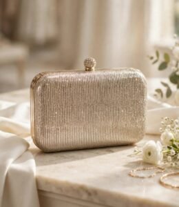 Golden shimmer party wear clutch bag with crystal clasp on marble table