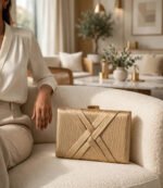 Golden party wear clutch bag with woven X design on cream sofa